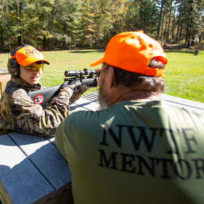 youth shooter learning how to properly use a firearm from a mentor