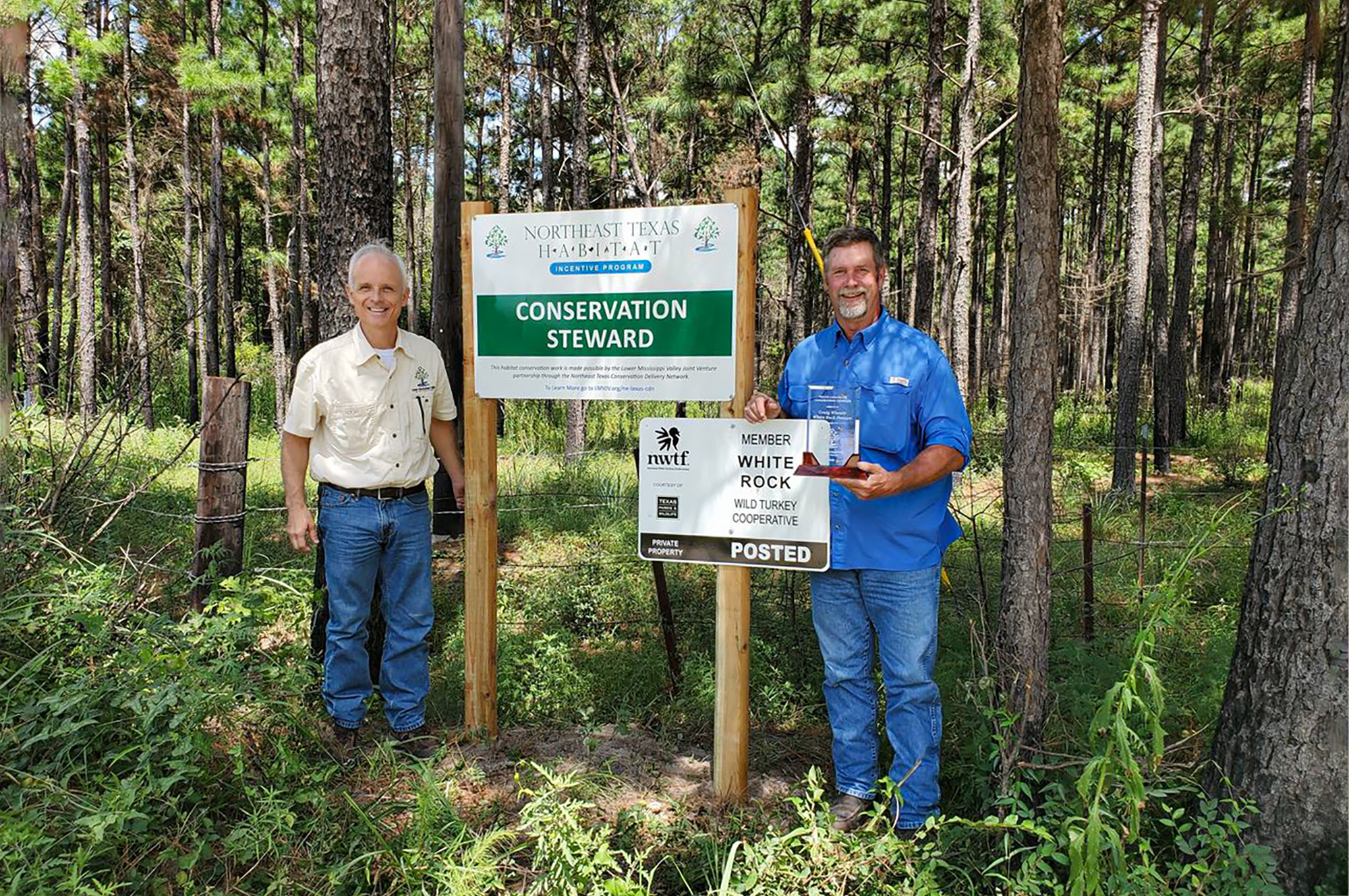 two adults standing at a conservation stewardship sign partially funded by the nwtf